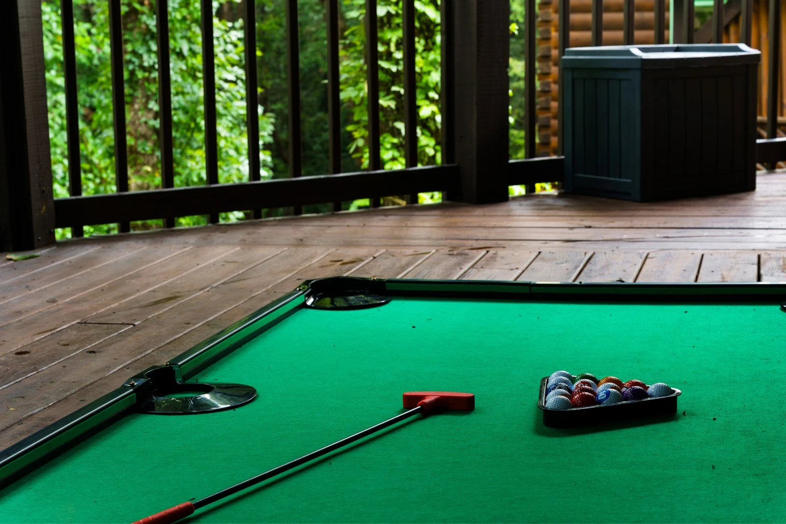 Putt-putt playing surface, putter and balls on the covered wooded deck